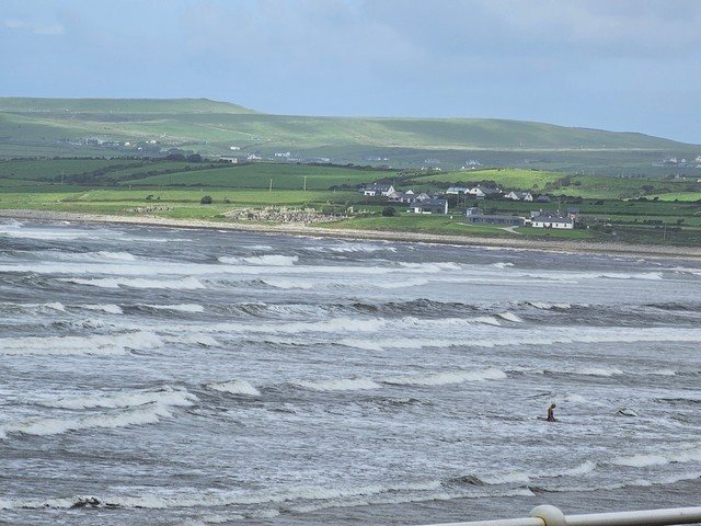 Big blown out swell all along the beach with one swimmer making their way out of the water